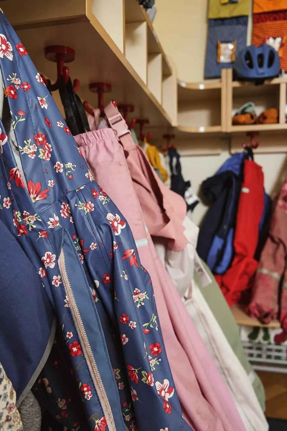 Garderobe mit bunten Kinderkleidern, Jacken und Mützen