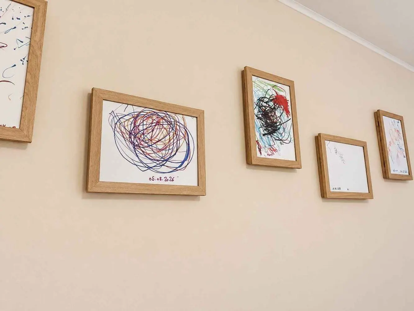Gerahmte Kinderzeichnungen hängen an einer hellen Wand