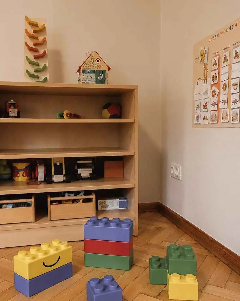 Regal mit Spielmaterial, davor große bunte Bausteine im Gruppenraum