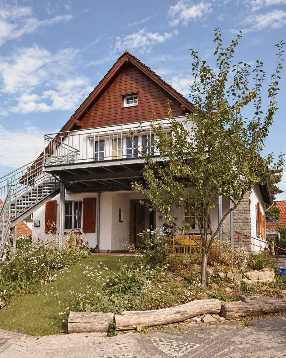 Das Haupthaus der Villa mit Balkon, davor ein Baum und eine Wiese