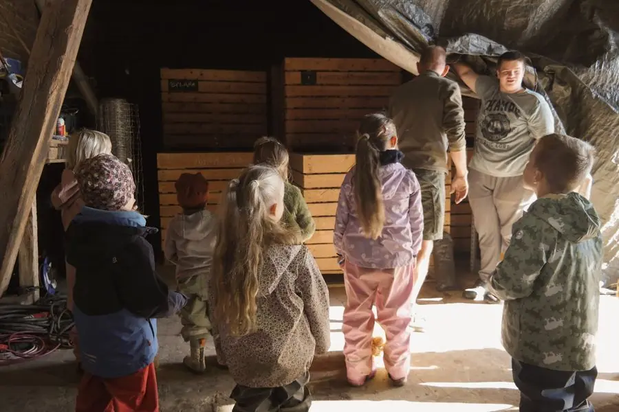 Die Kinder stehen im Lager vor großen Holzkisten für Kartoffeln