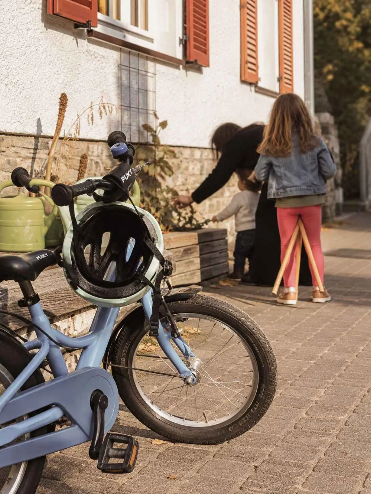 Ein Kinderfahrrad mit Helm steht im Vordergrund, im Hintergrund erntet ein Kind etwas