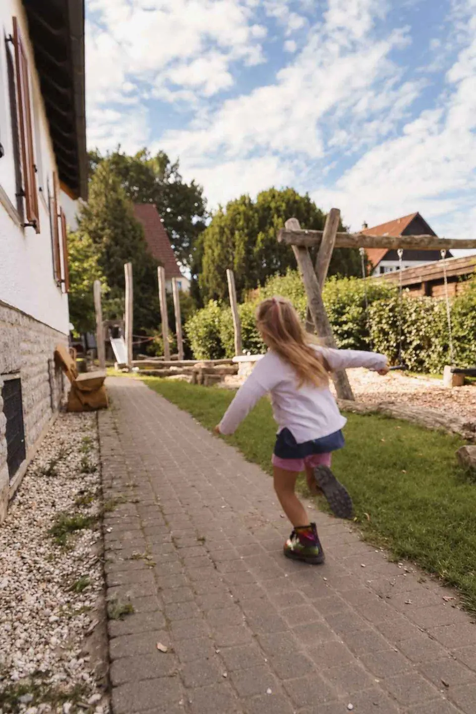 Ein Mädchen rennt über den gepflasterten Gartenweg