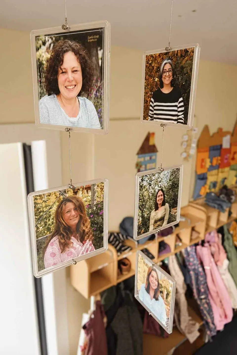 Porträtfotos des Teams hängen als Mobile über der Garderobe