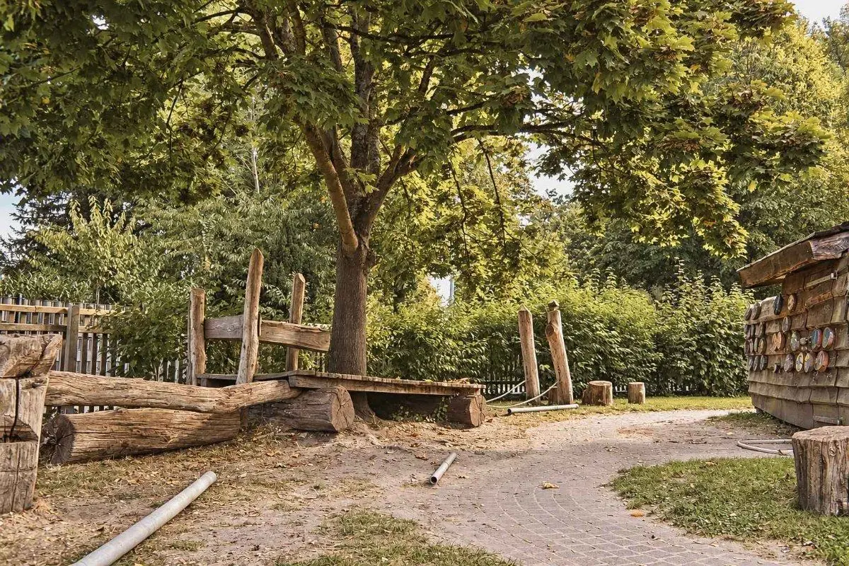 Naturnaher Spielbereich im Garten mit Baumstämmen und einem Sandweg