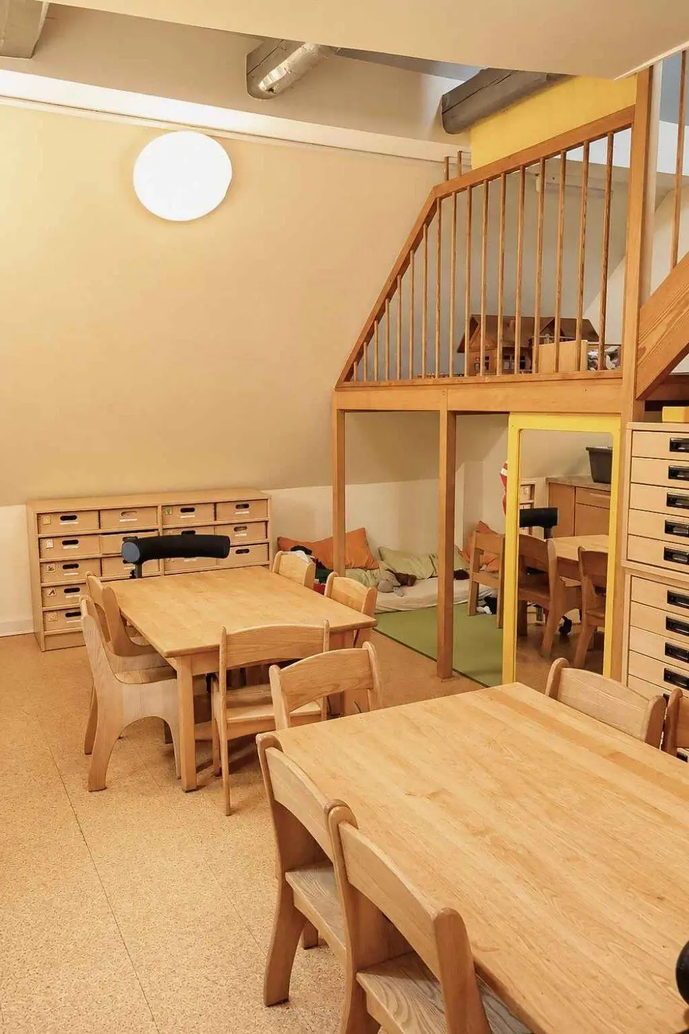 Gruppenraum mit Holztischen, Stühlen und einer Hochebene